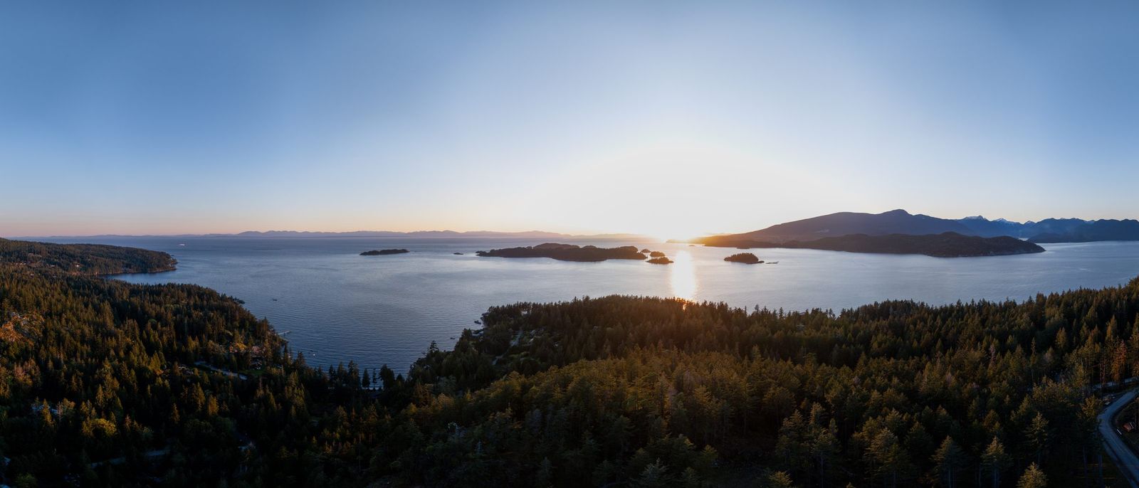 Sunset over the water from above Arbutus Ridge, Bowen Island, headlands in silhouette